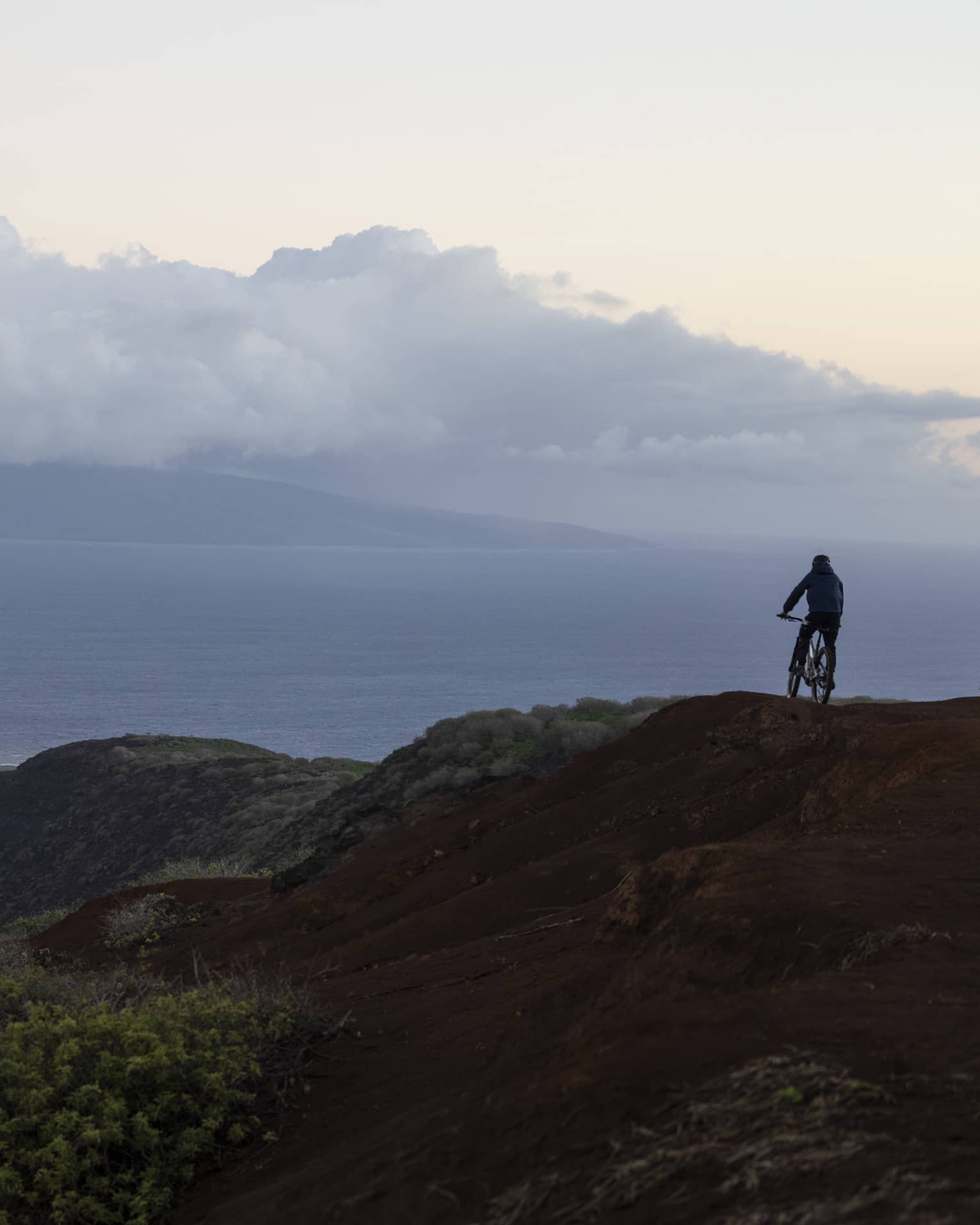 A person rides mountain bike on rugged, tropical terrain