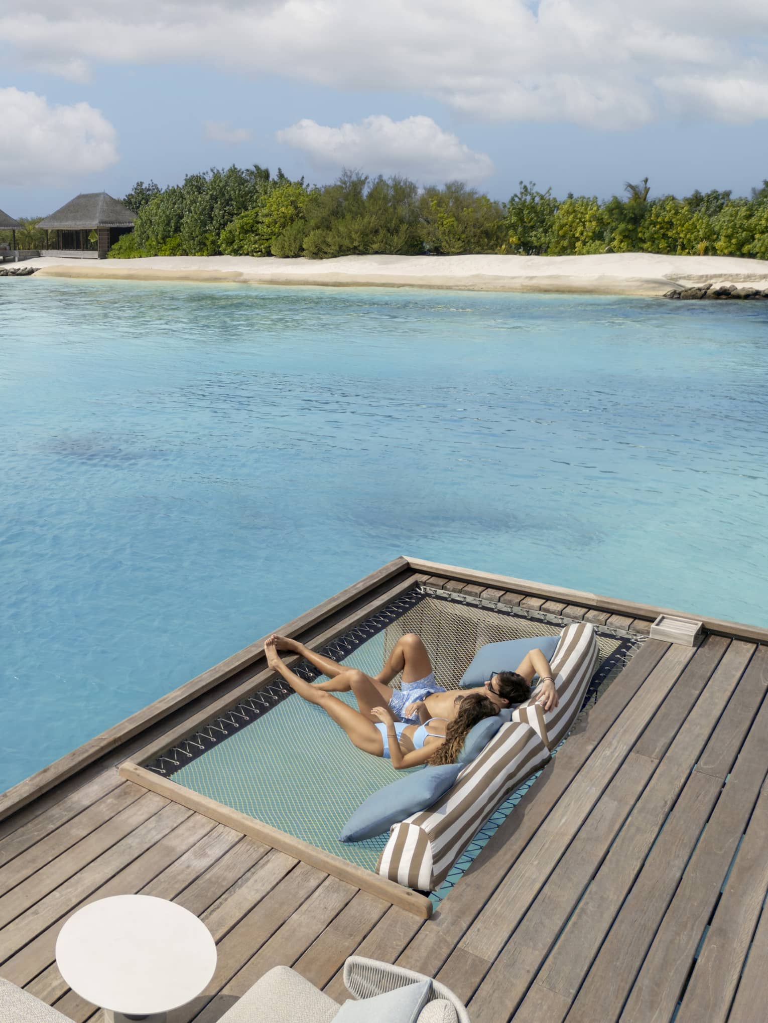 Two people lounge on sundeck as ocean spans out in front of them
