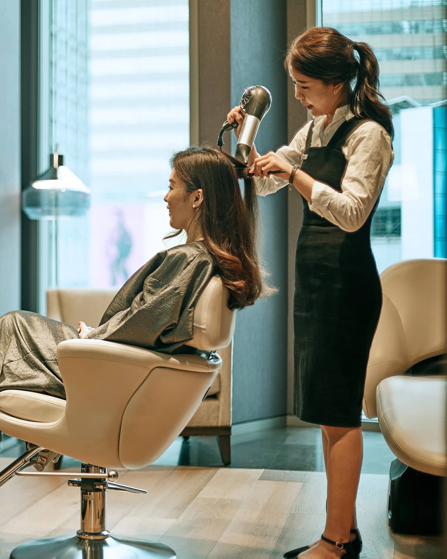 Hair stylist blow dries woman's hair in hotel salon