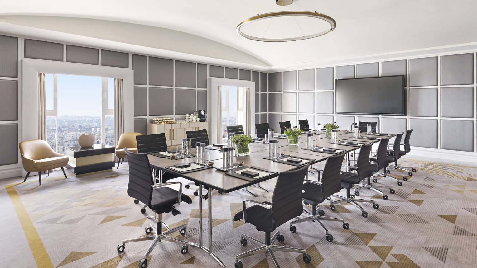 A conference room with a long table in the centre, and chairs surrounding one all sides. 