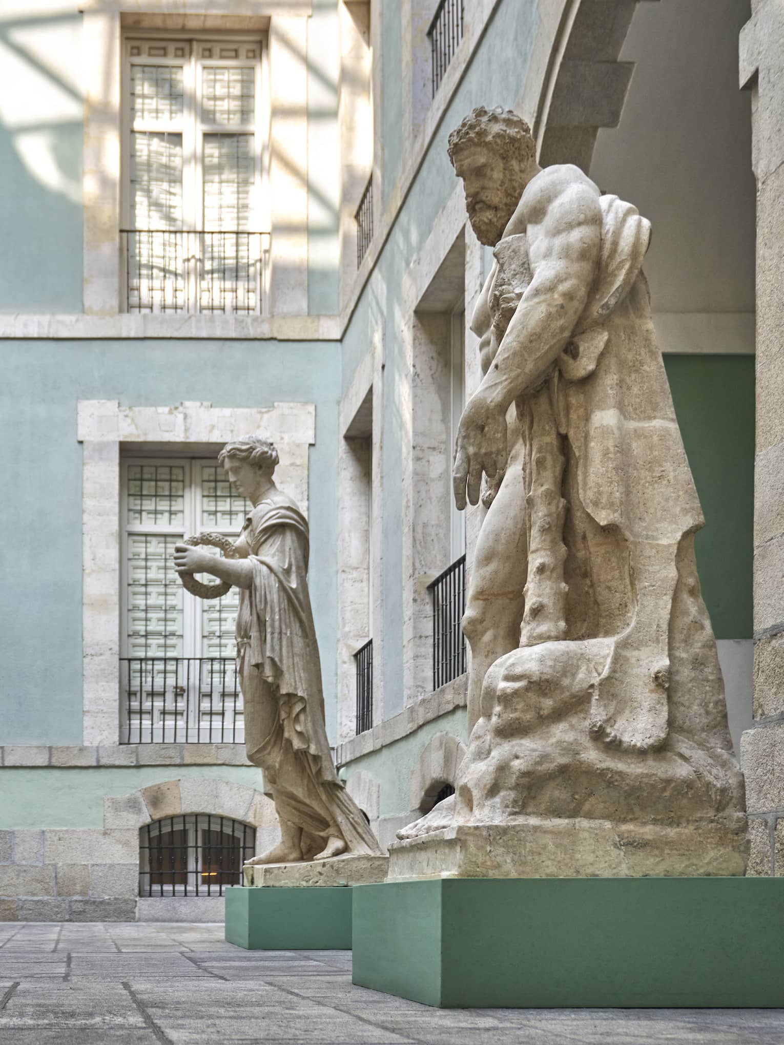 Two women observe large sculptures in a courtyard surrounded by light blue building