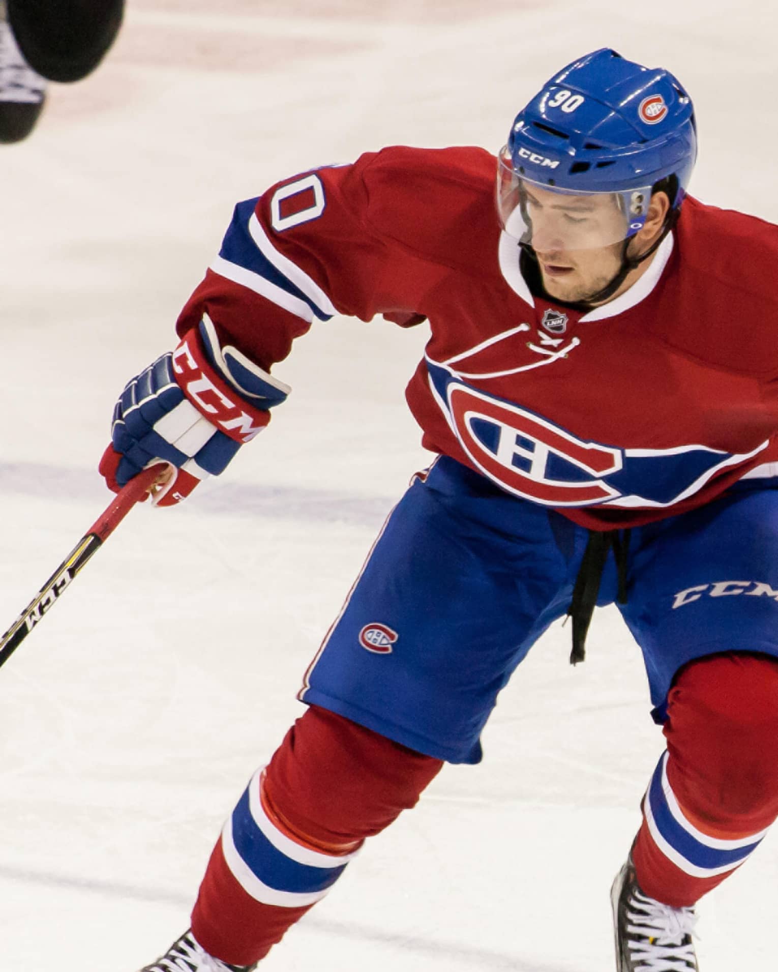 Montreal Canadiens NHL hockey player skates on ice with stick, puck
