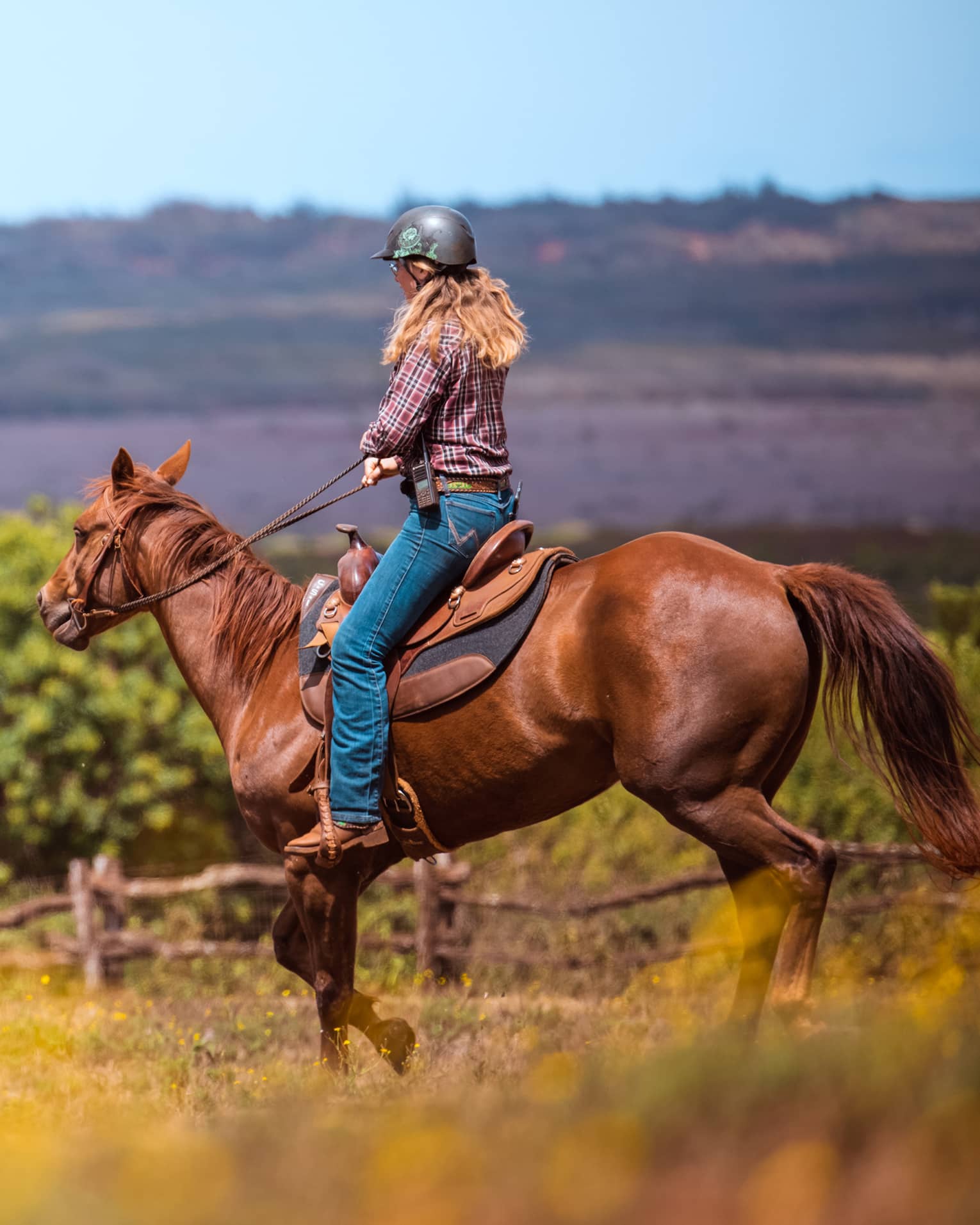 A woman horseback riding in a mountain landscape