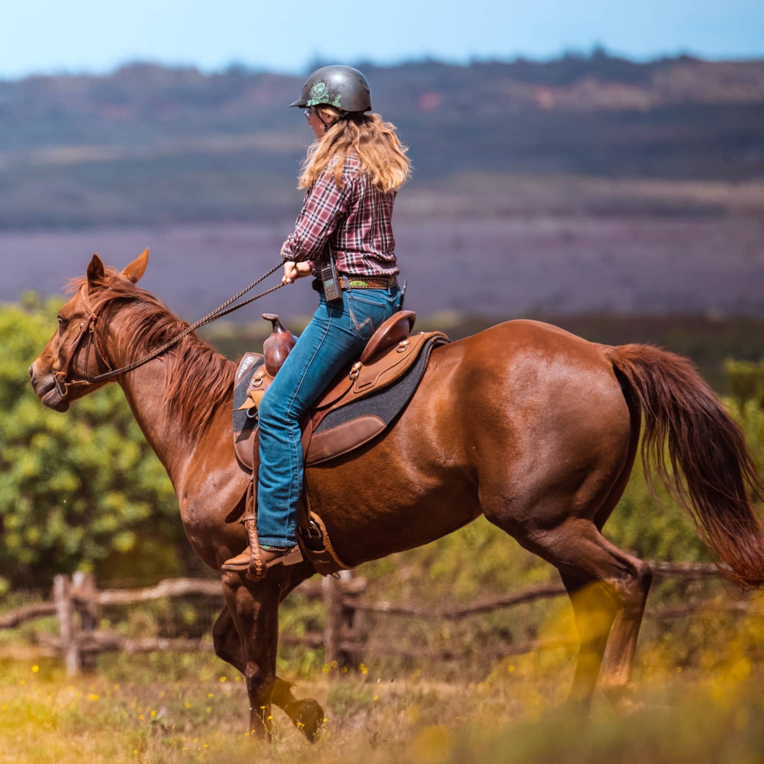 A woman horseback riding in a mountain landscape