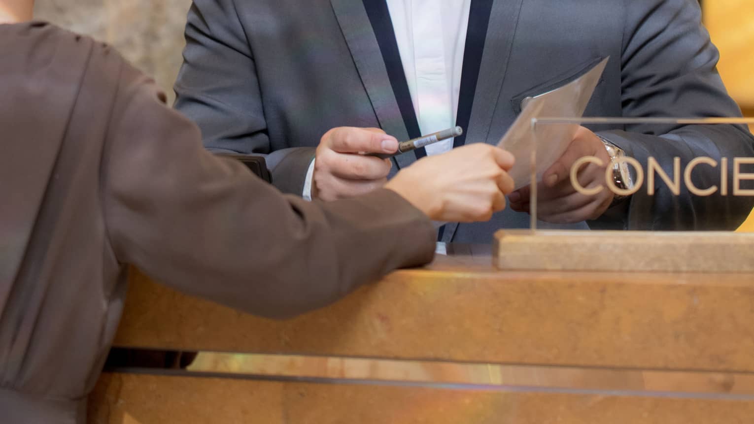 A concierge assists a guest at a marble desk