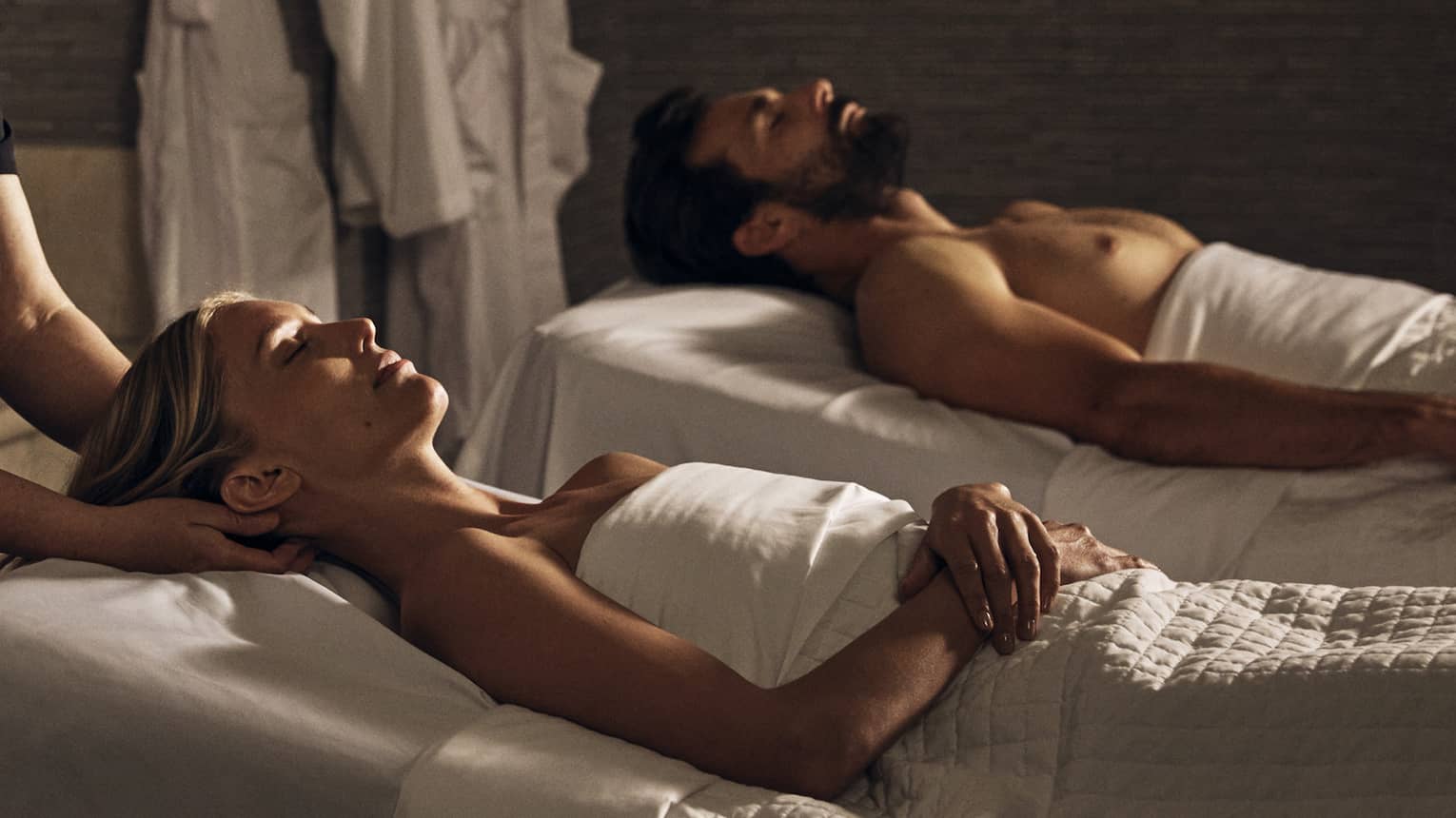 Two guests laying on massage tables in a room with a spa tub.