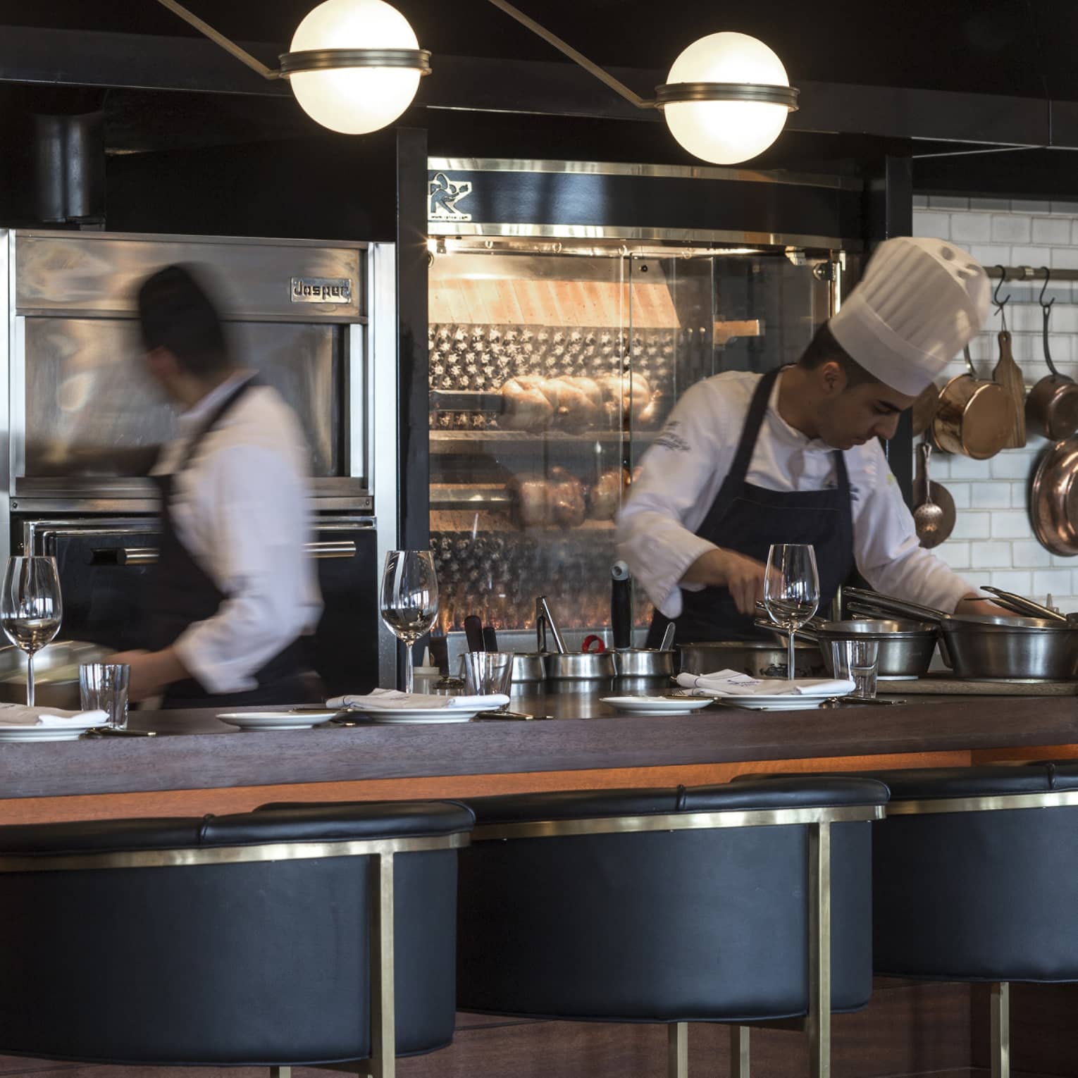 Chefs working behind a counter with black-and-gold stools in the foreground