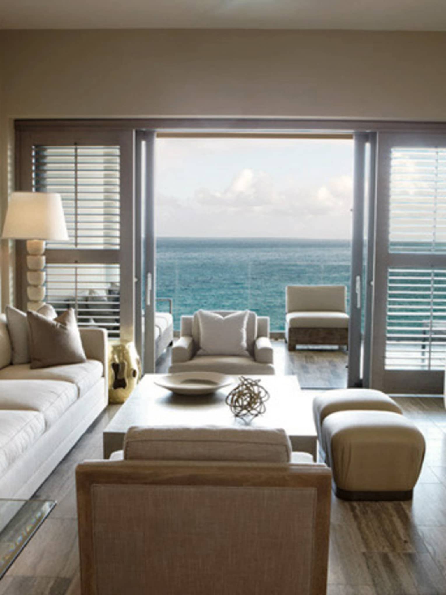 Modern living room with neutral décor, large glass doors and ocean view balcony