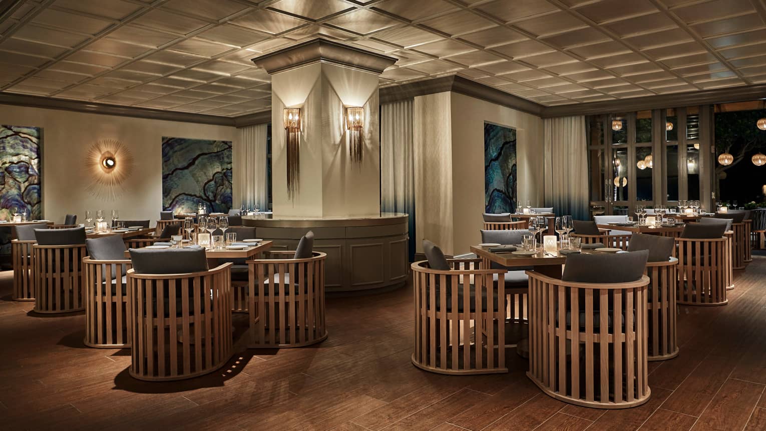 Noe dining room with modern wood chairs around tables, modern lights on pillars