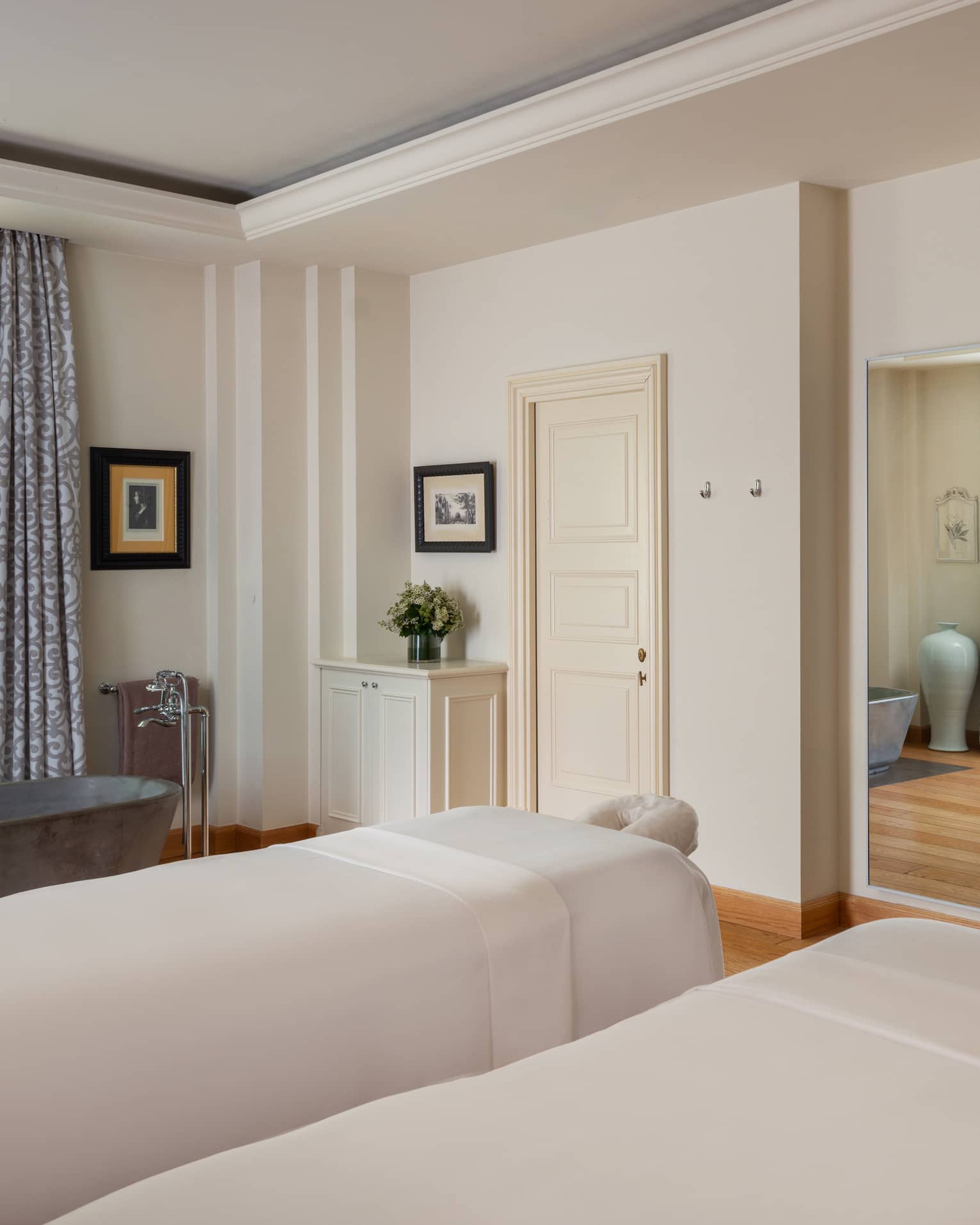 A light and spacious spa treatment room with two treatment tables side by side