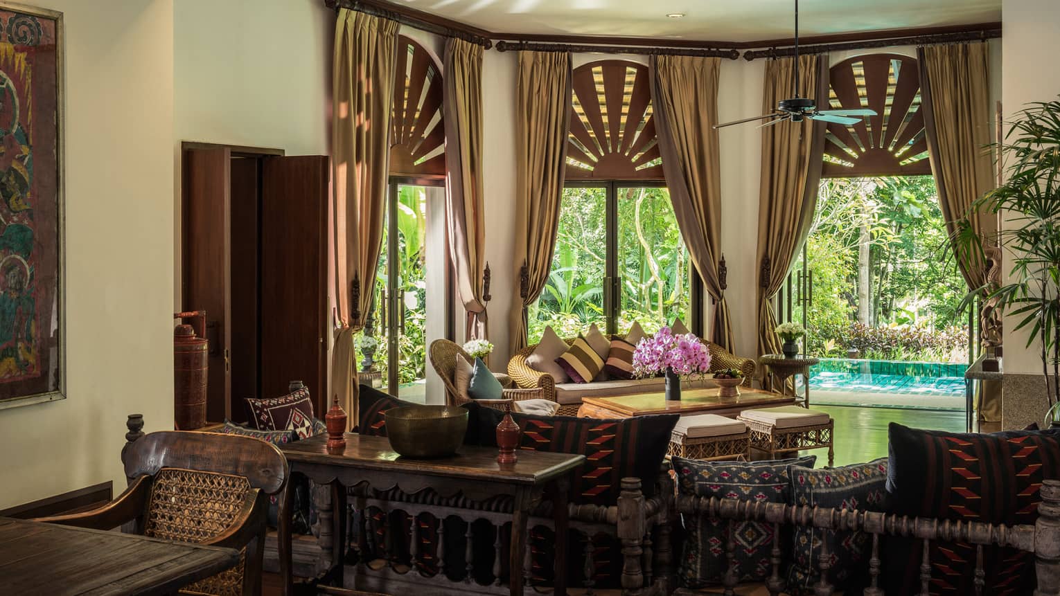 Tall bay windows with gold curtains over sofa, living room, plunge pool visible on patio