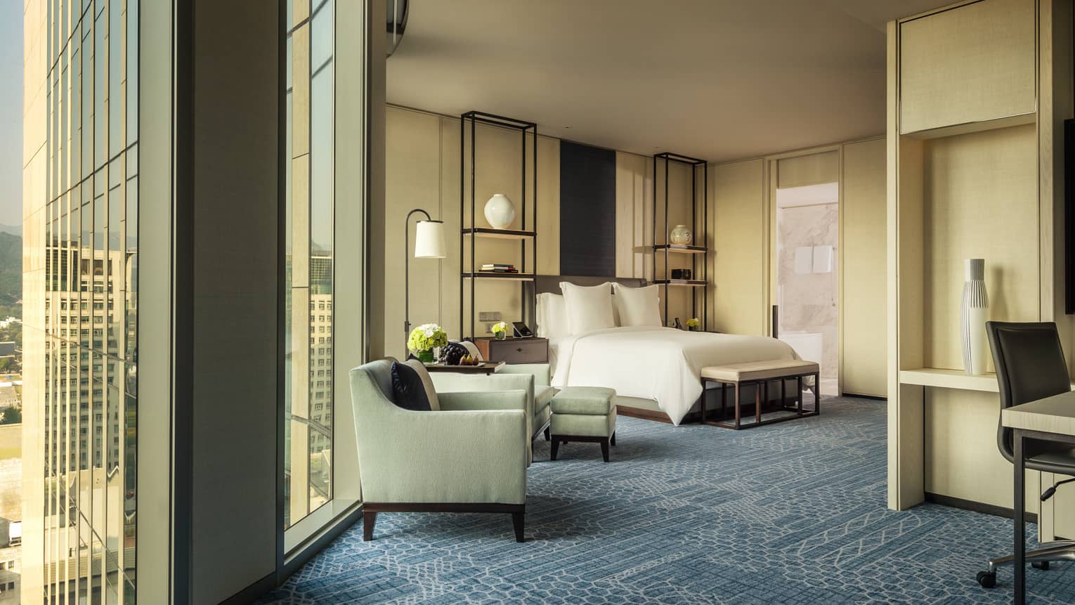 Studio Suite armchairs by tall windows, hotel bed, alcove with work desk