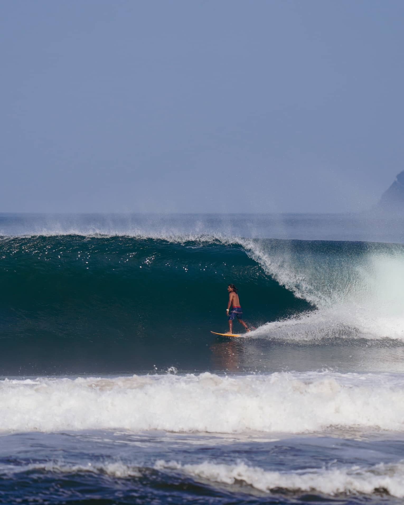 Man surfing under a large wave