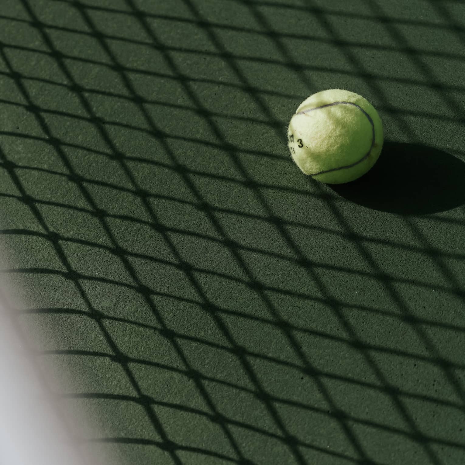 Tennis ball on tennis court with shadow of net