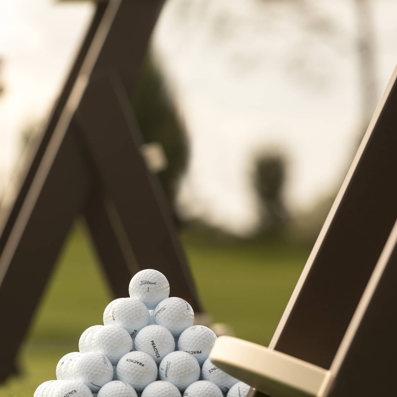 Stacks of white golf balls on lawn in front of wood panels