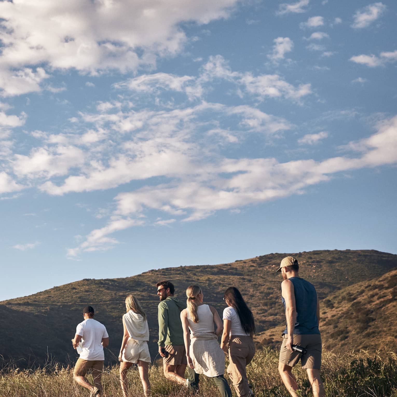 A group of people hiking along a mountain on a sunny day.
