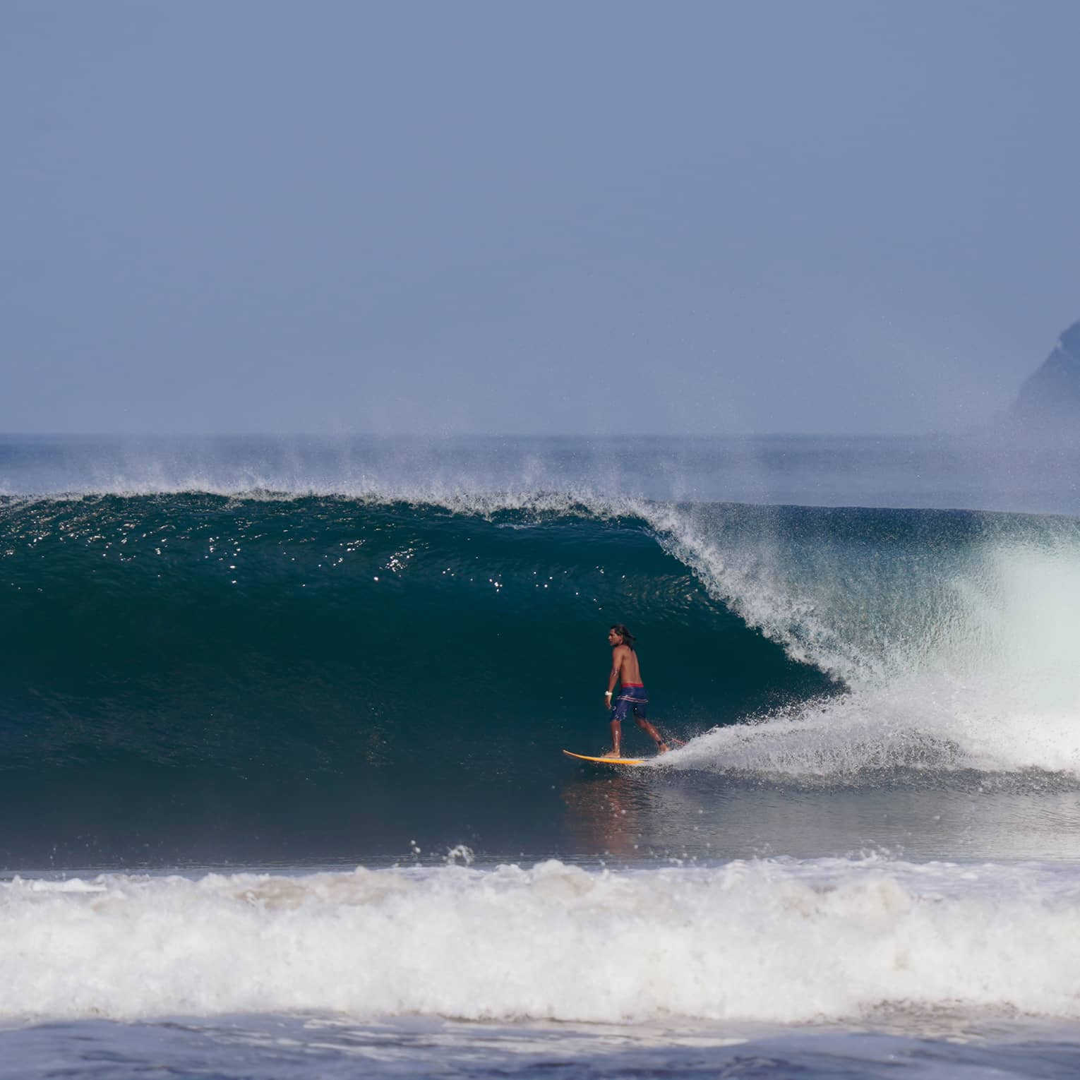 Man surfing under a large wave