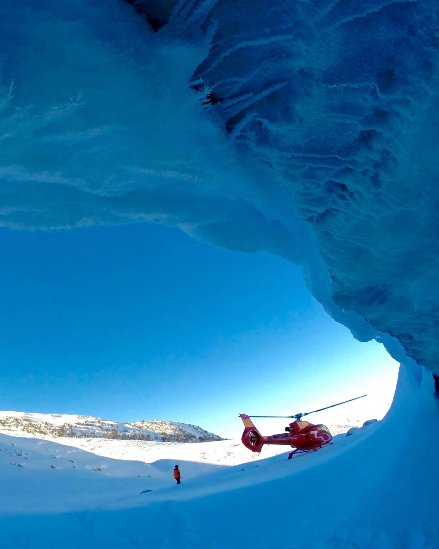 Helicopter against striking blue sky at opening of ice cave