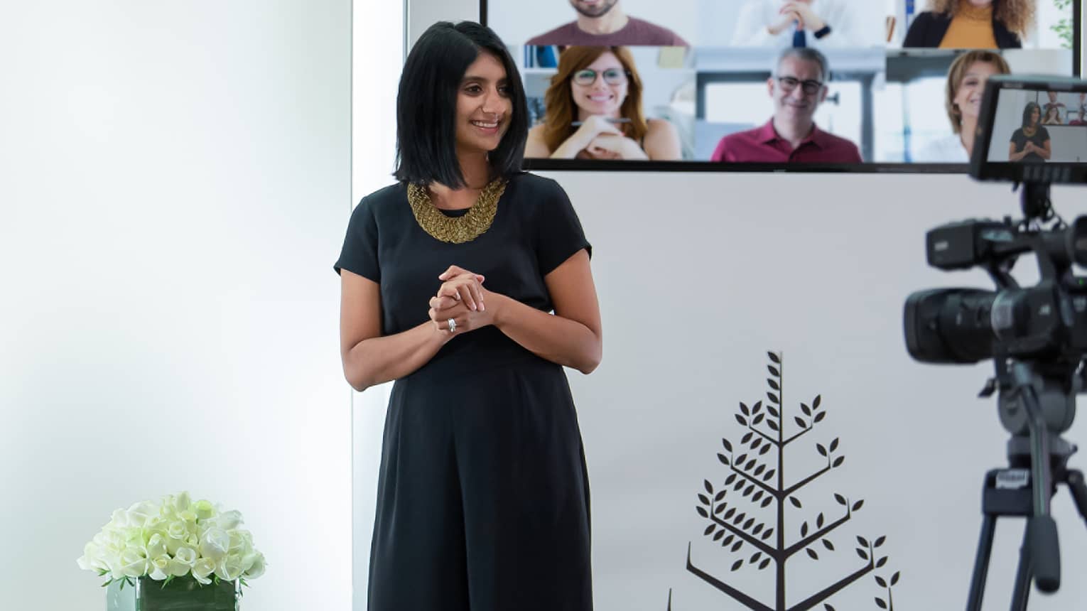 Several people host a virtual meeting in a room with the Four Seasons logo.