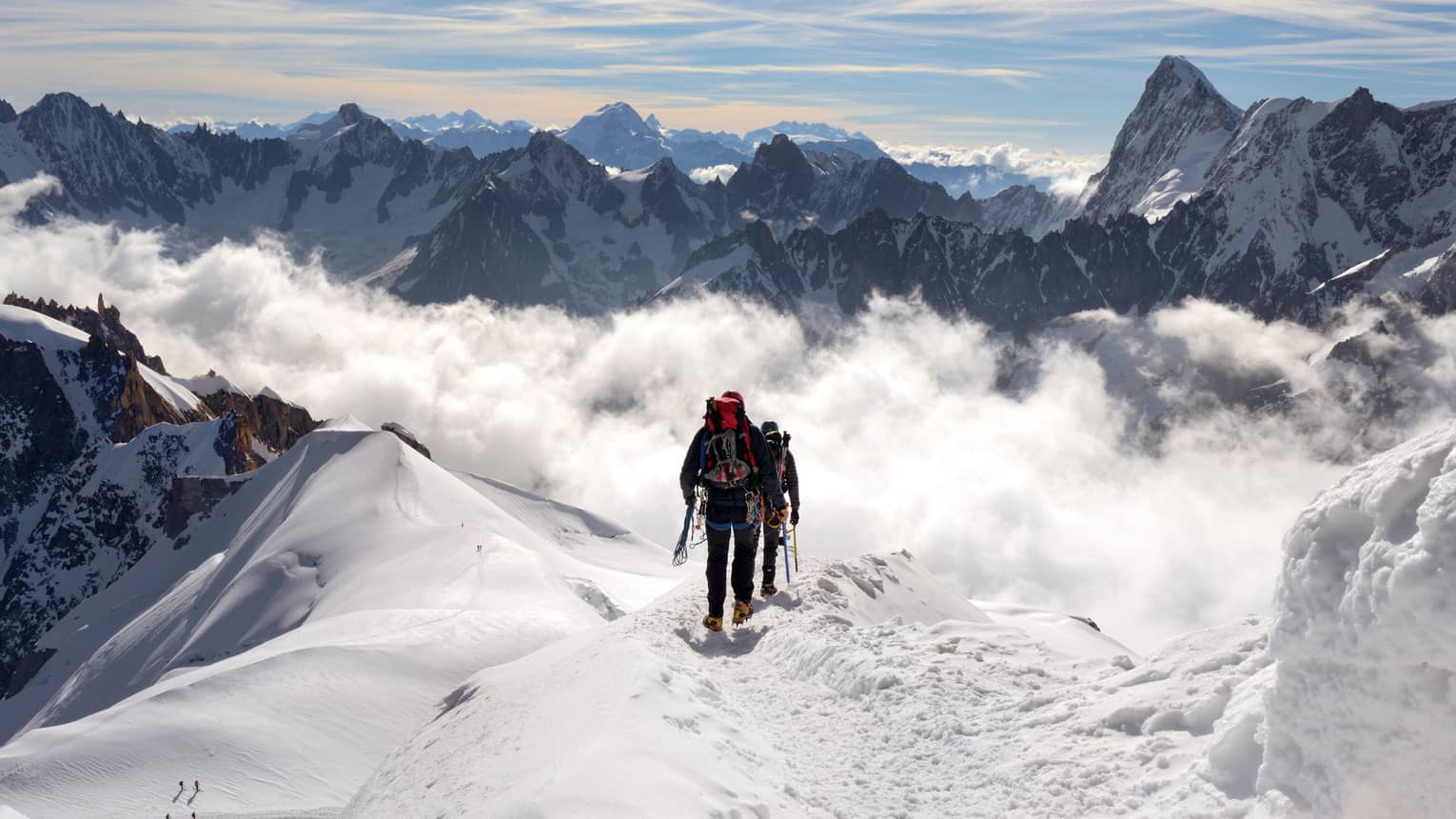 Two people hiking at top of icy mountain in French Alps