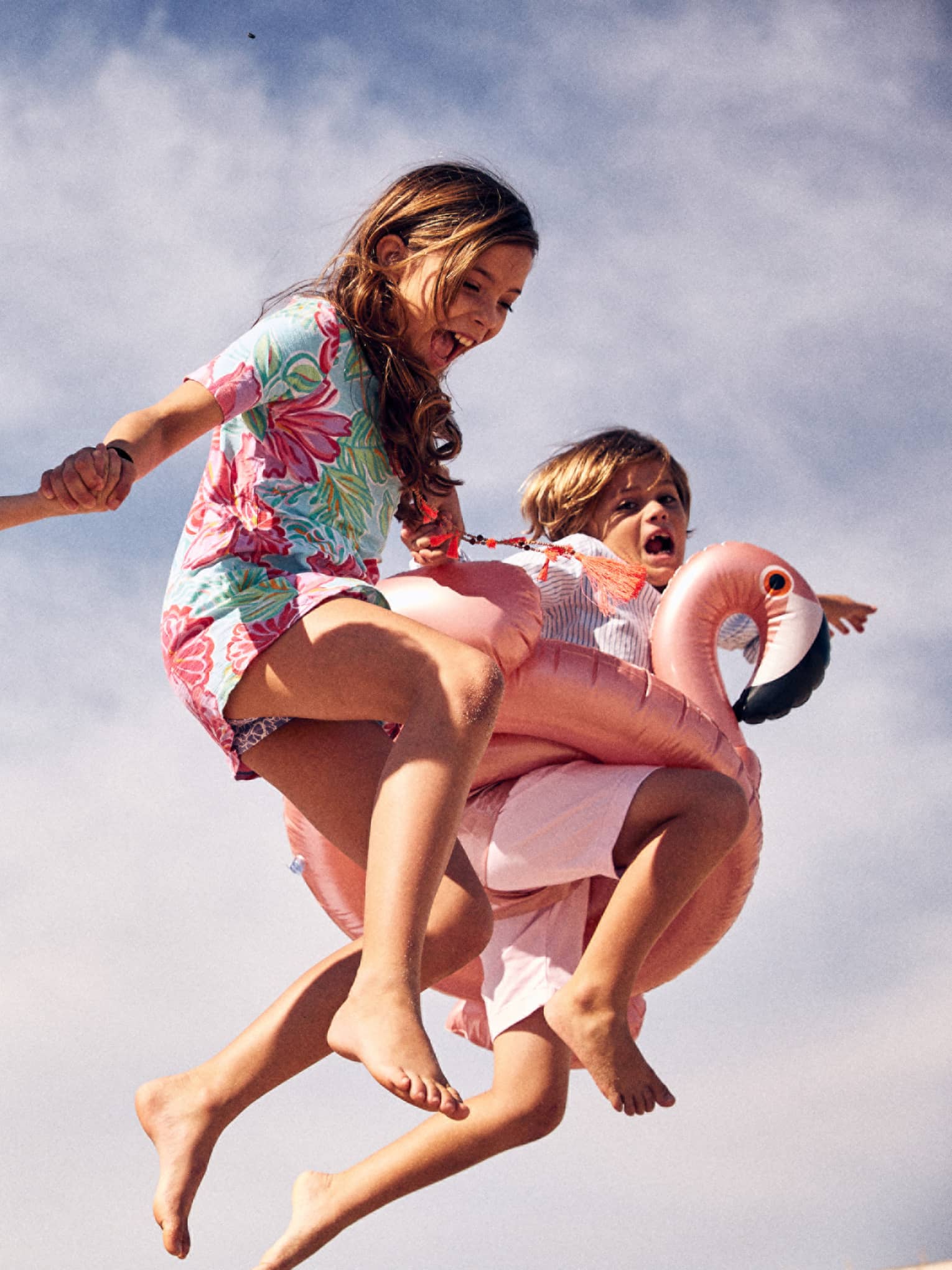 Three young children jump through the air on the beach