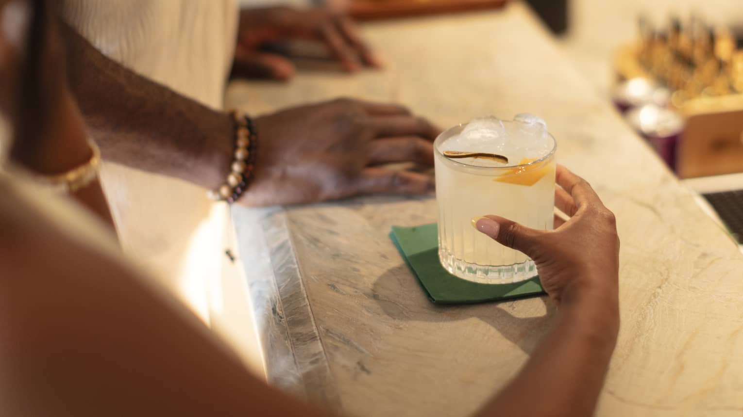 A person holds a cocktail on a marble bar