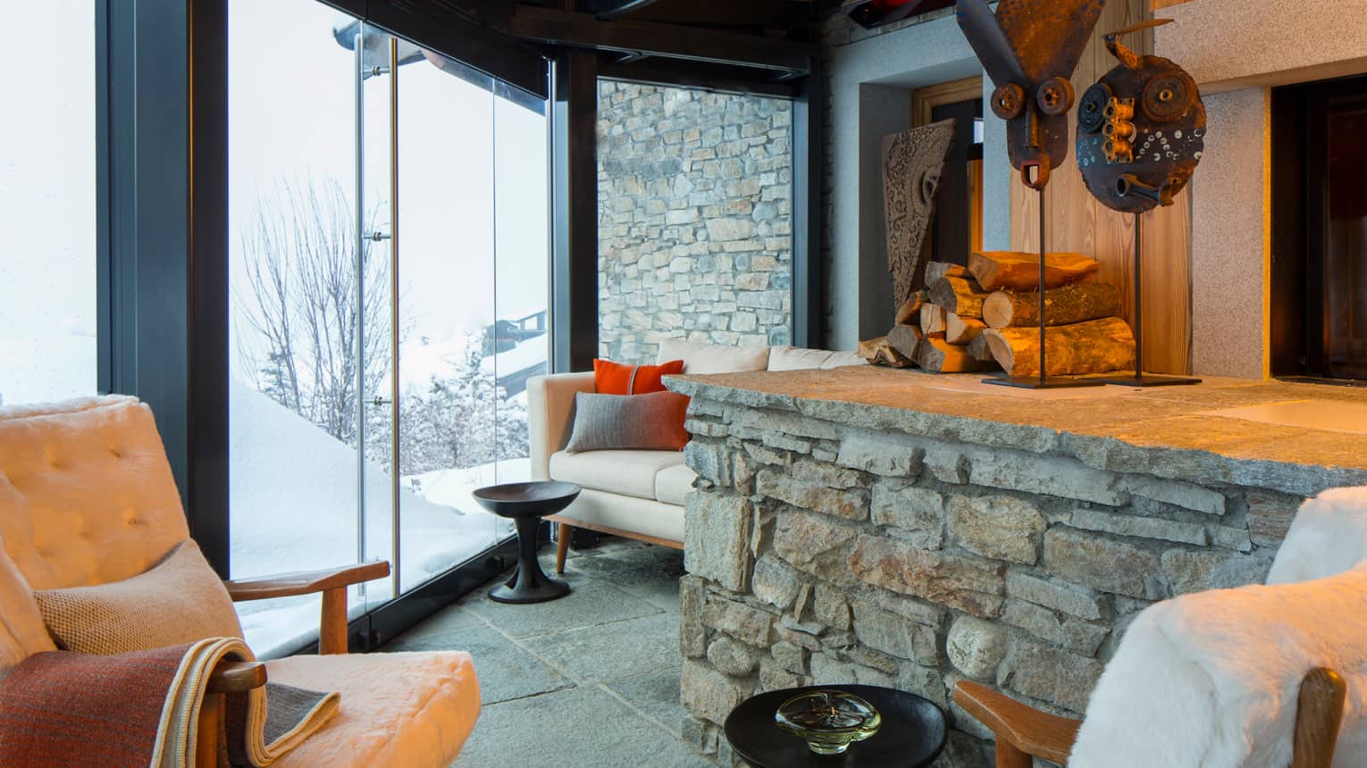 Cigar Room plush white lounge chairs by stone ledge with logs, sculptures, gas fireplace