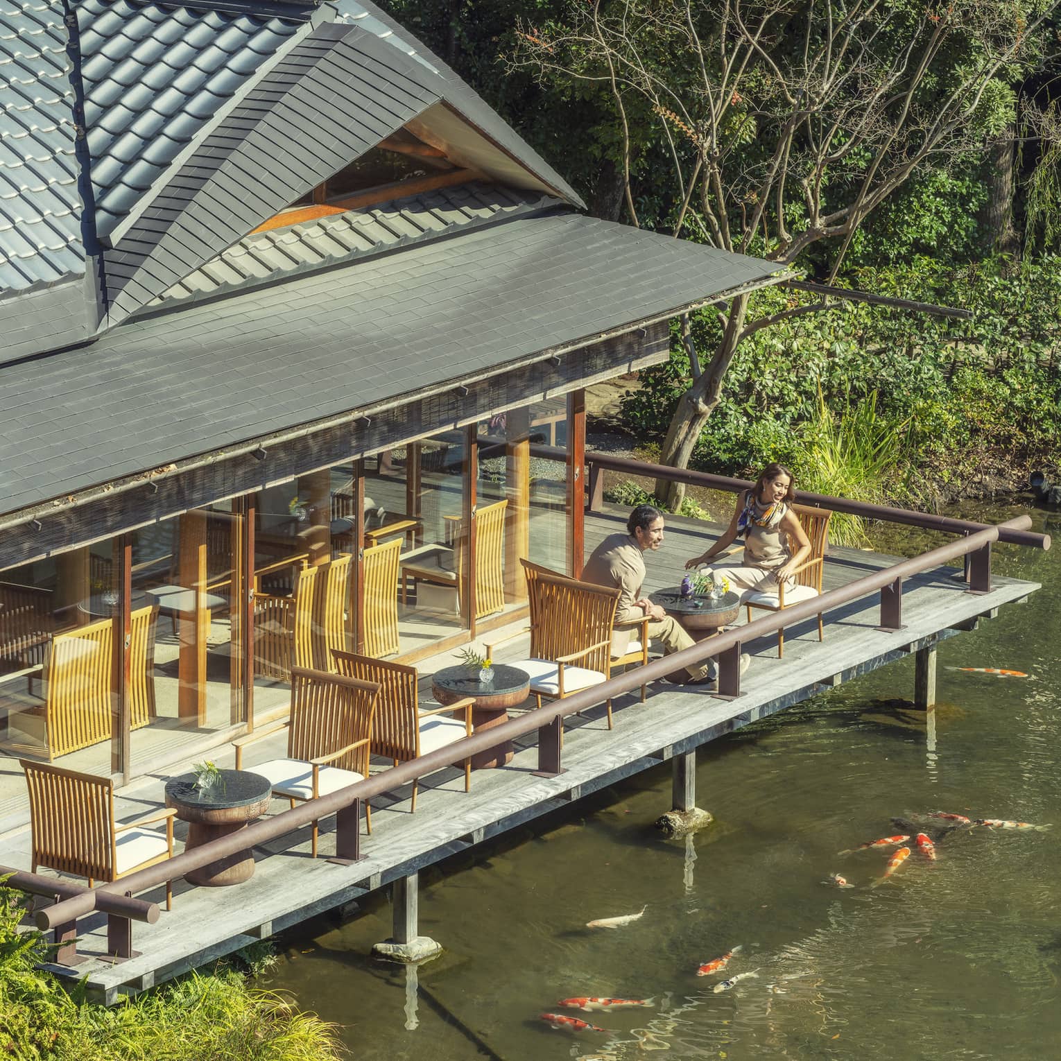 Two people sitting on an outdoor deck overlooking a pond with koi fish at Four Seasons
