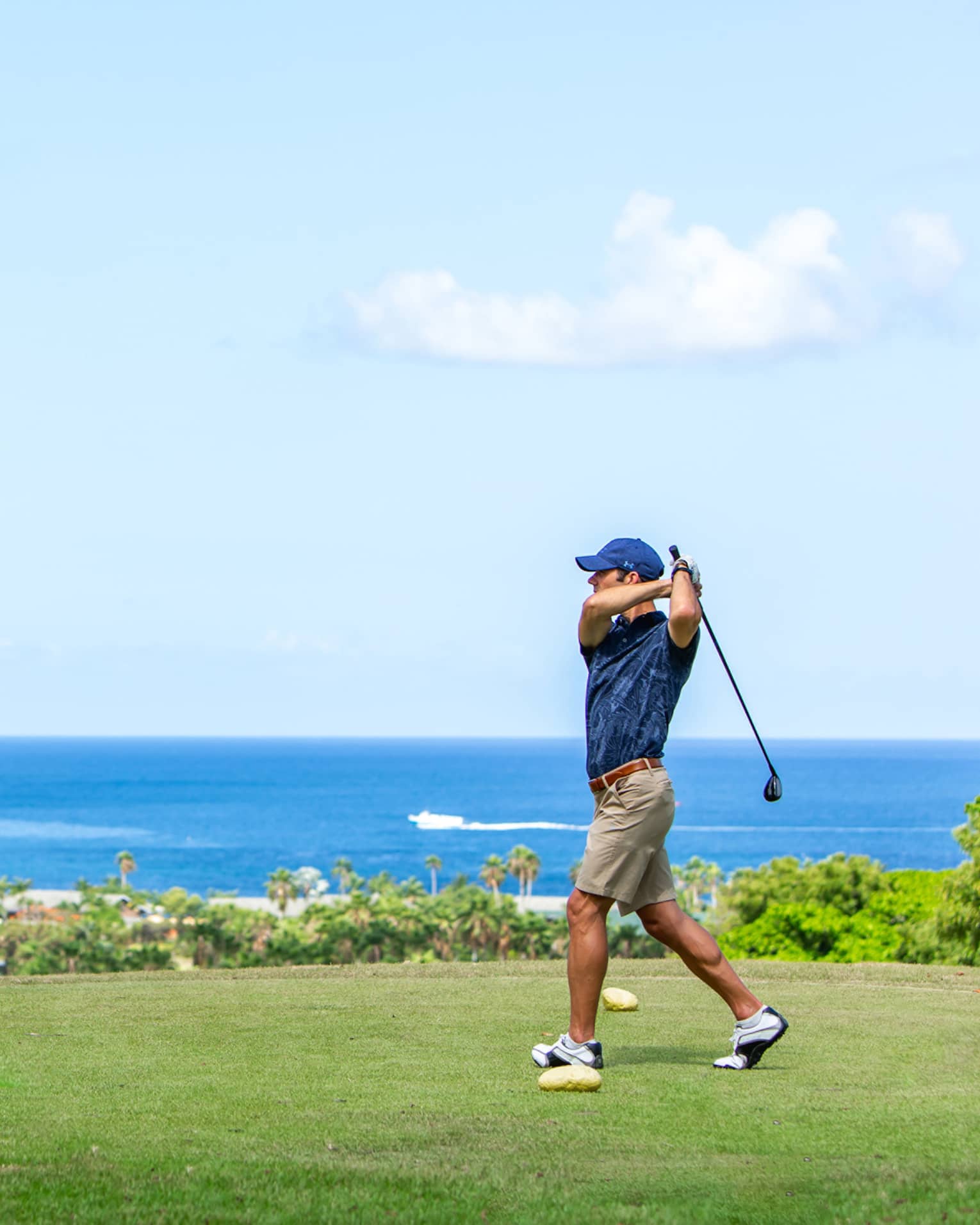 A man golfing near an ocean.