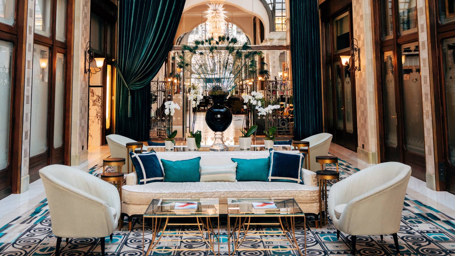 Zrínyi Passage with Zsolnay tiles, white chairs and couch, blue cushions, drapes and high ceiling