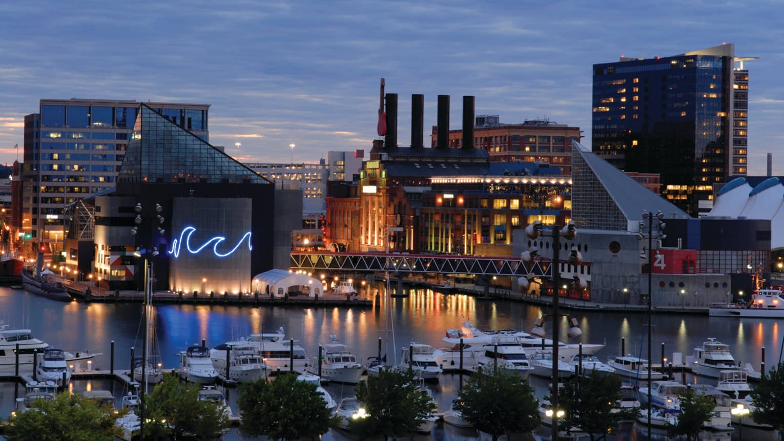 Baltimore buildings with fluorescent wave lights, boats in harbour at dusk
