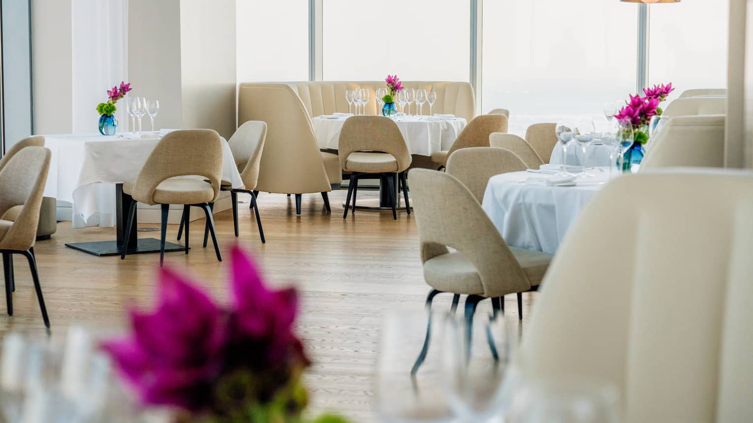 Brightly lit dining room with pink flowers on every table
