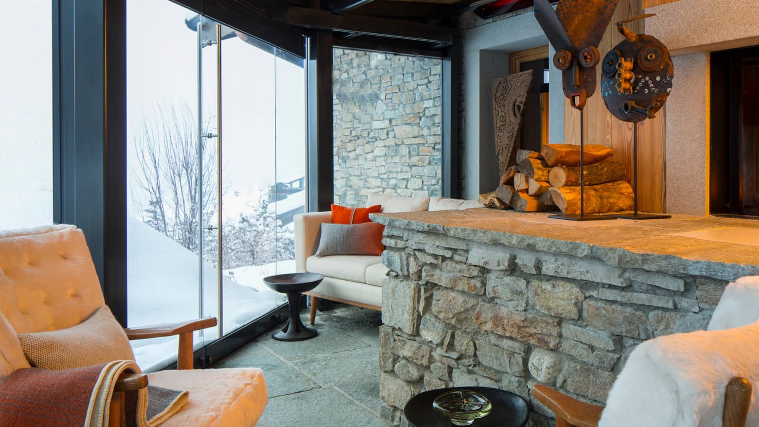 Cigar Room plush white lounge chairs by stone ledge with logs, sculptures, gas fireplace