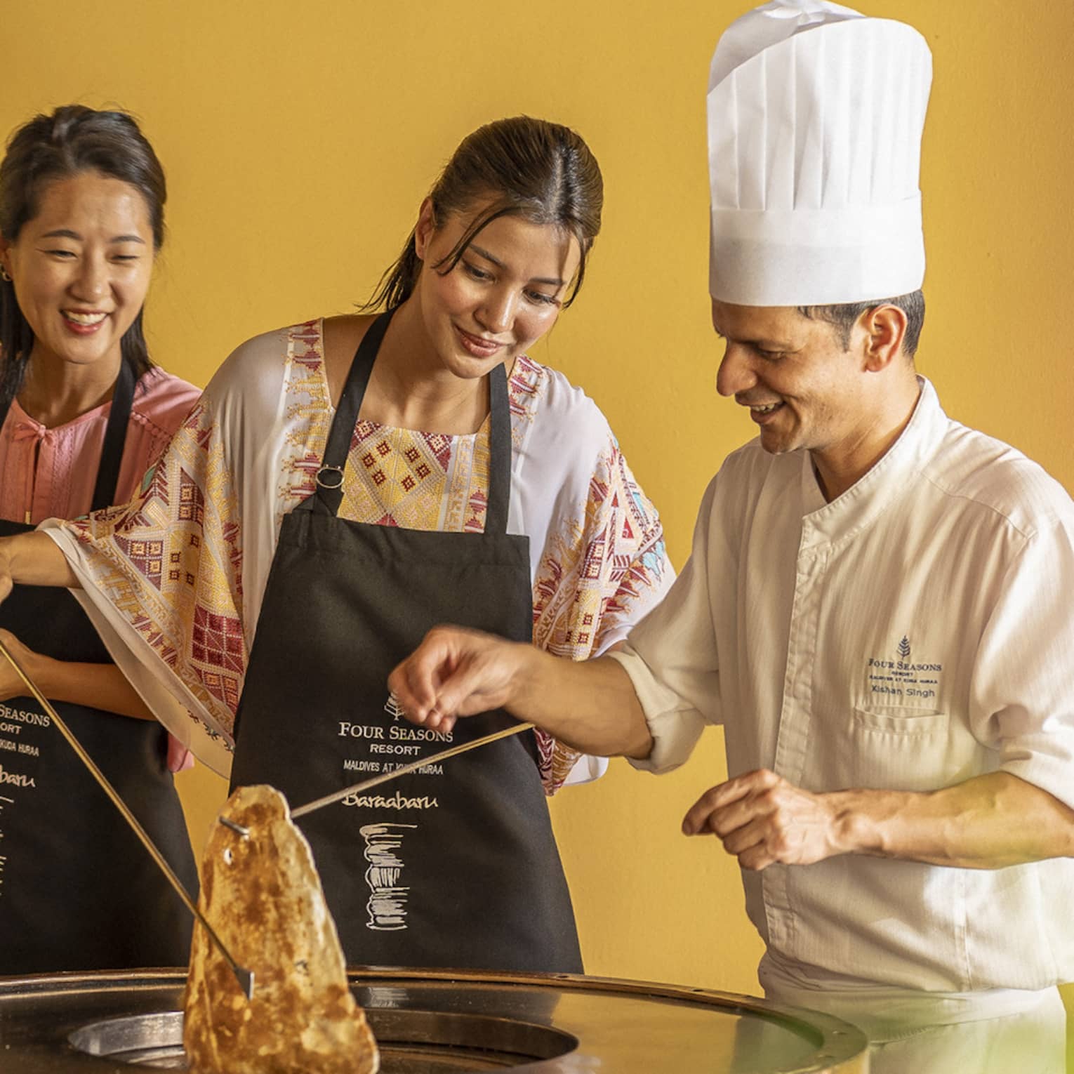 Chef teaches two female guests during Indian cooking class at Baraabaru