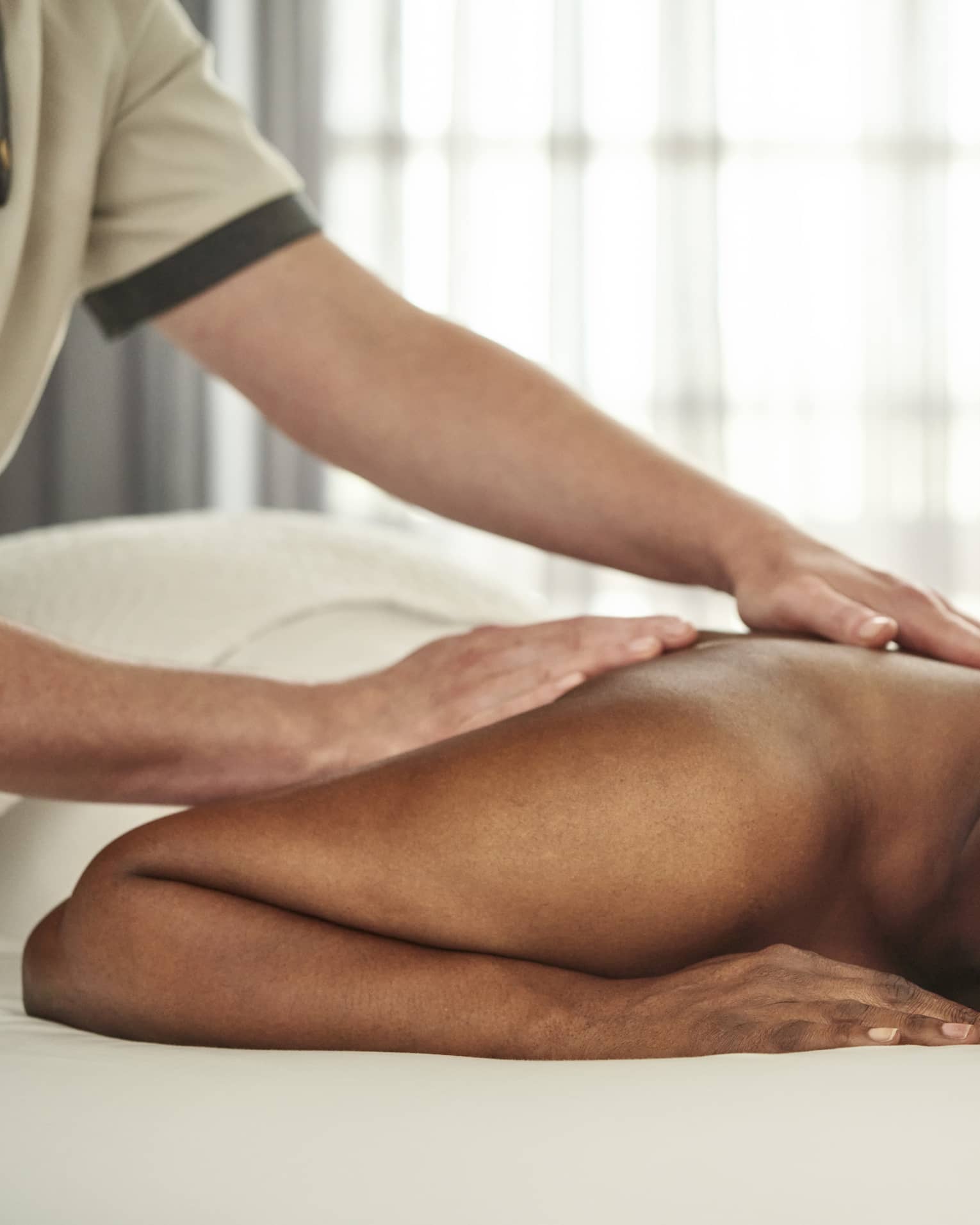 A person getting a massage in a well lit treatment room.