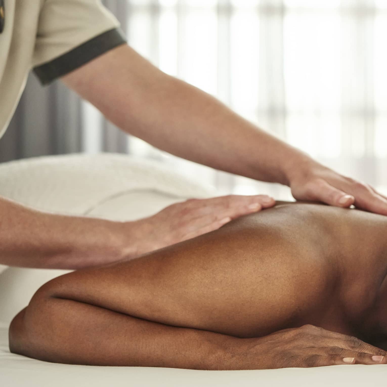 A person getting a massage in a well lit treatment room.