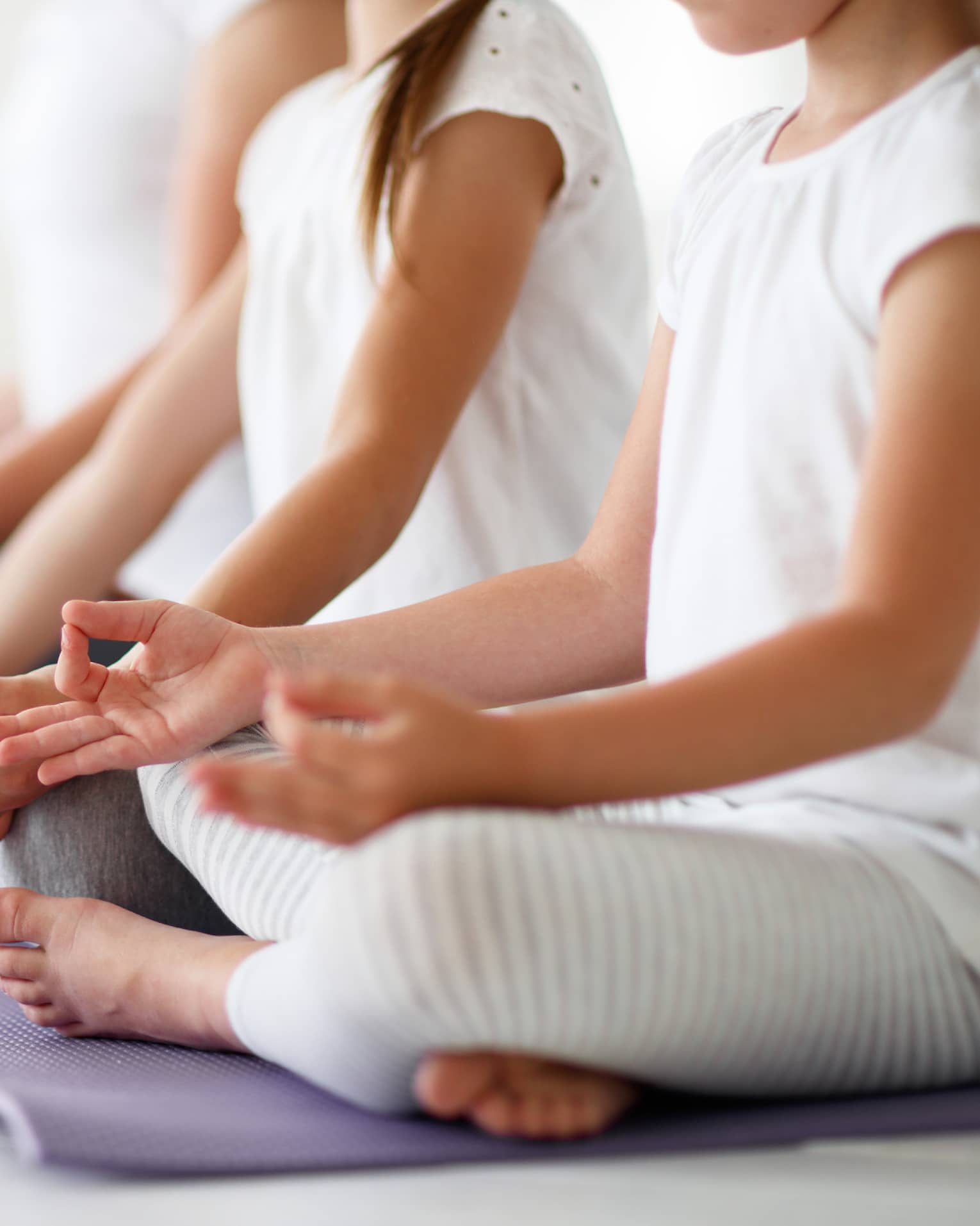 Young girls sit in cross-legged yoga pose