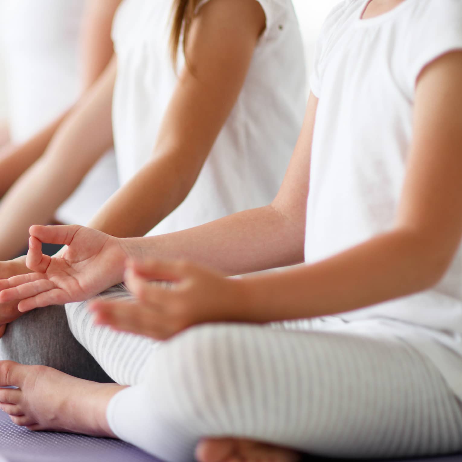 Young girls sit in cross-legged yoga pose