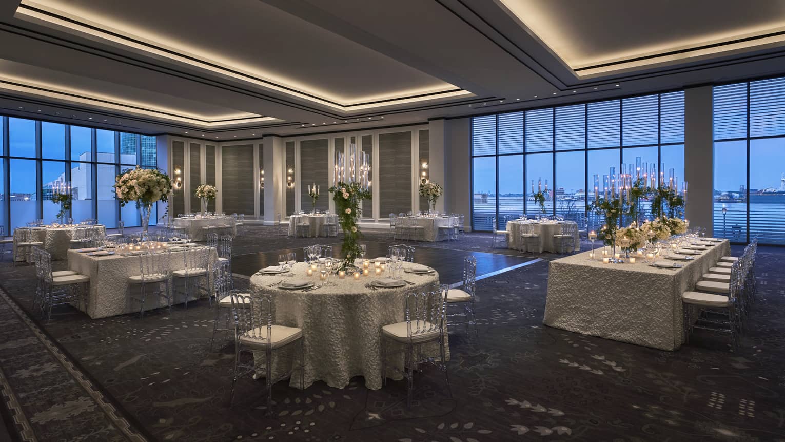 Ballroom with half-rounds and rectangular table, yellow floral centrepieces, floor-to-ceiling windows with views of the Mississippi River