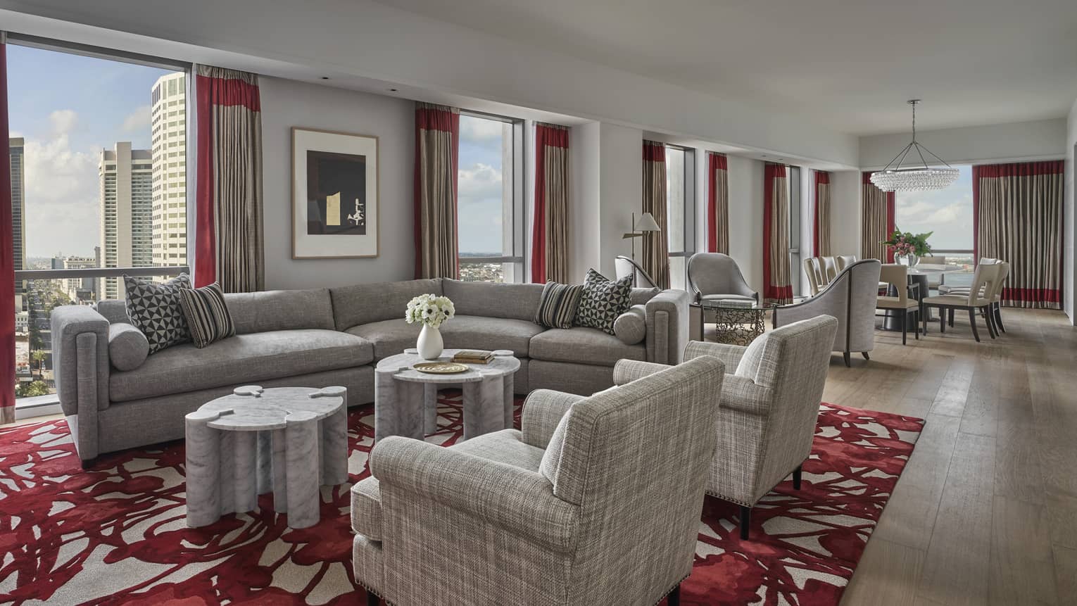 A living area with a large sofa, two chairs and large windows. inside a luxury suite in New Orleans