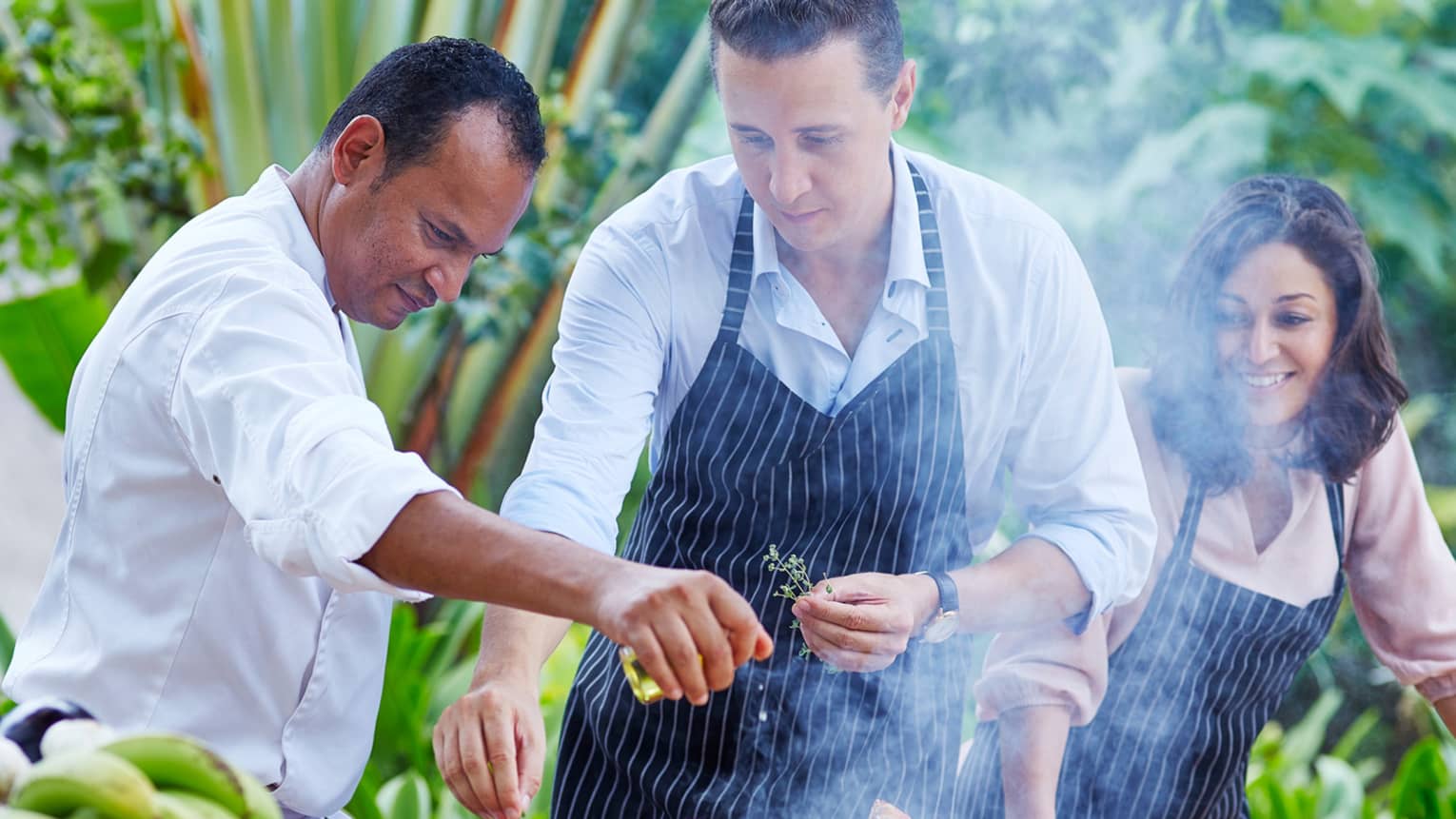 Chef, couple wearing aprons garnish meat, vegetables on outdoor grill