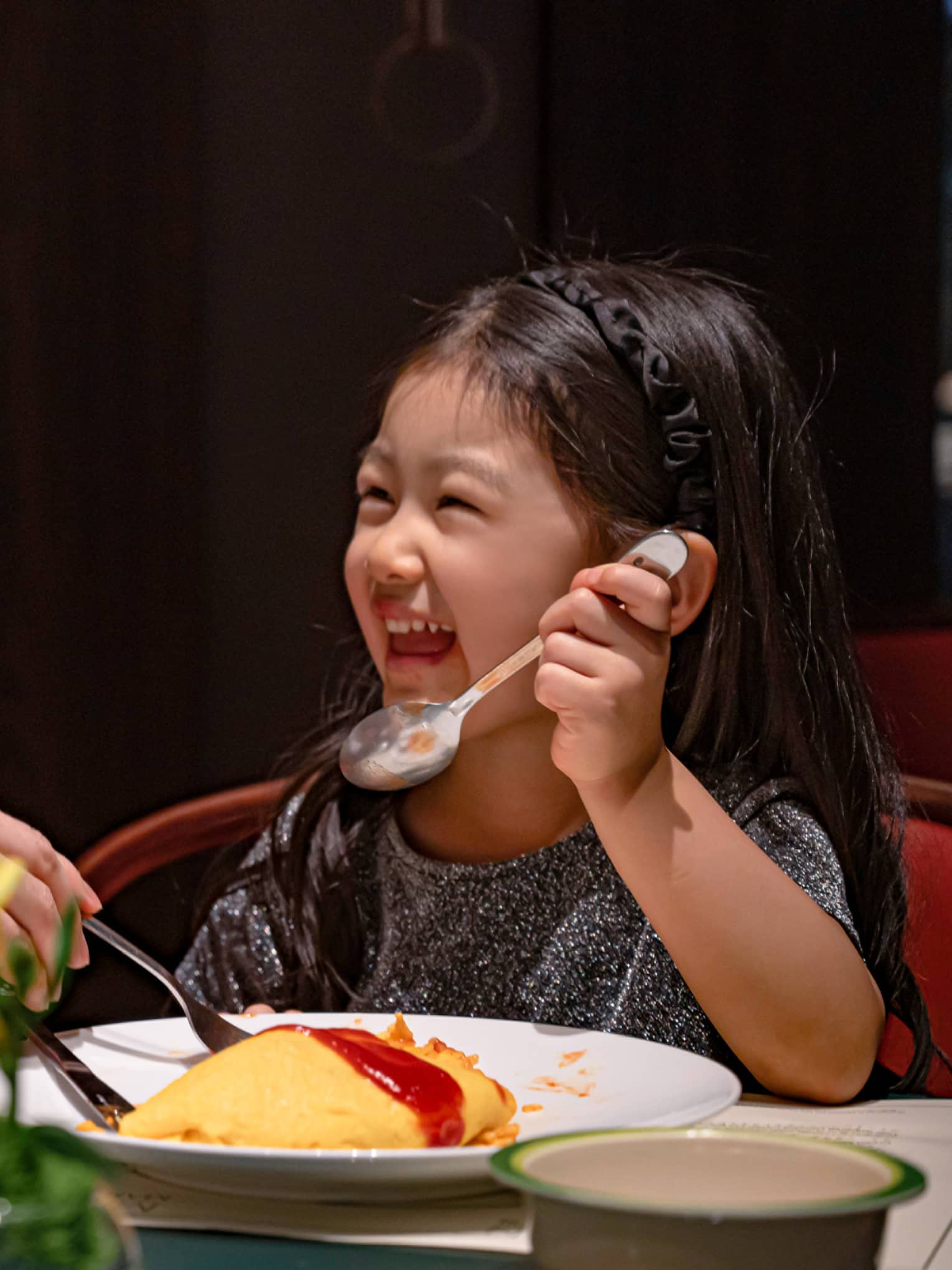 Smiling young girl and her dad dig into omurice topped with ketchup