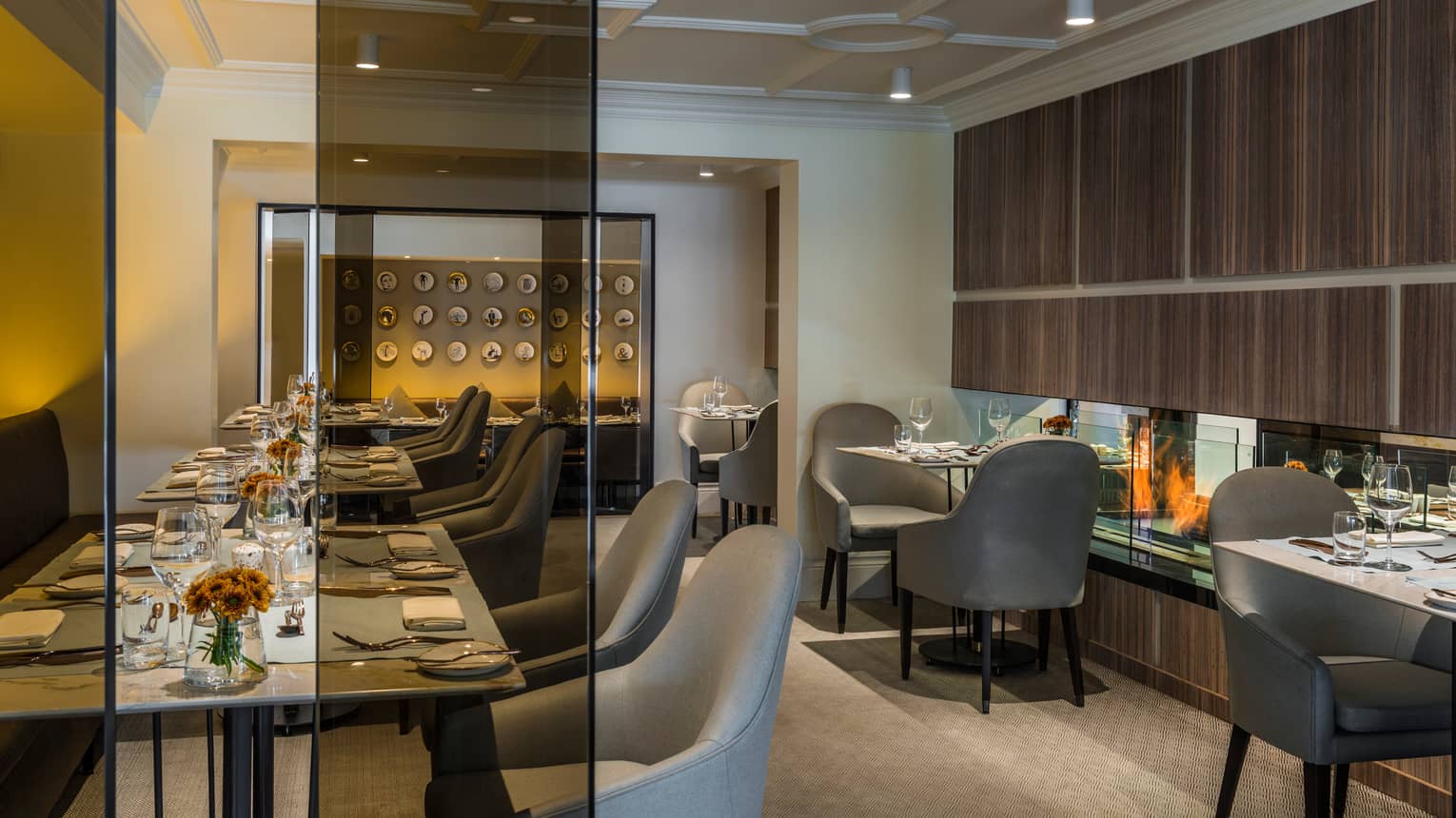 Formal dining tables, grey chairs in indoor restaurant, glass panel wall