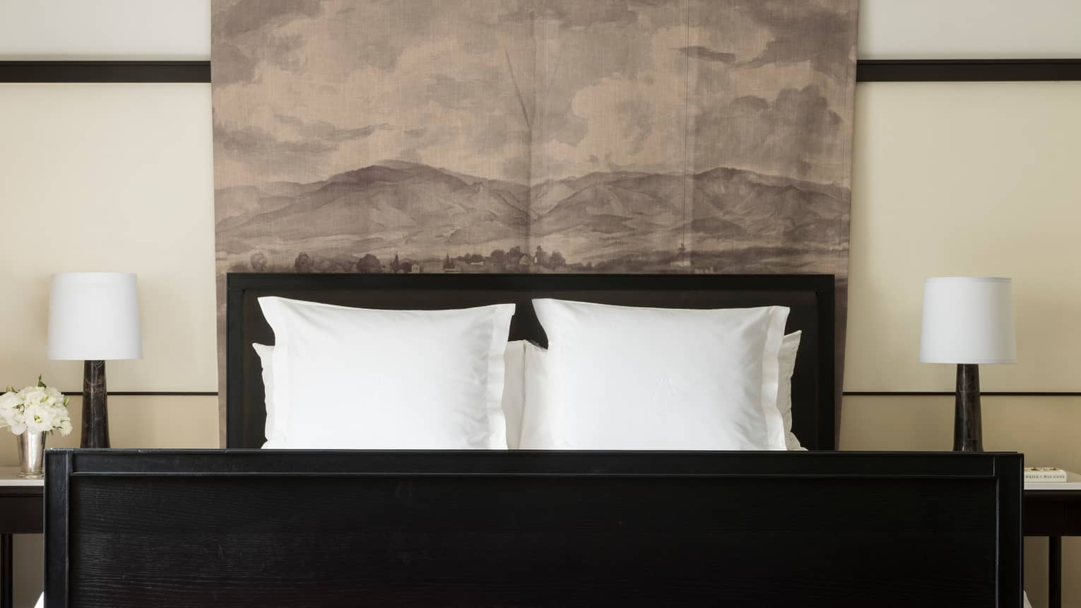 Executive Suite black bed, reading lamps under padded headboard with landscape print