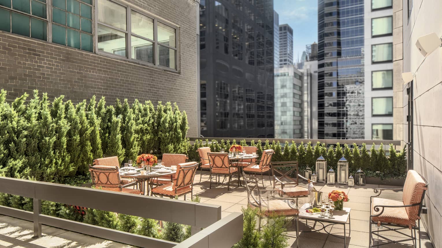 11th Floor Terrace Boardroom, surrounded by green topiaries, with square iron and glass tables with orange cushions on chairs at Four Seasons Hotel New York