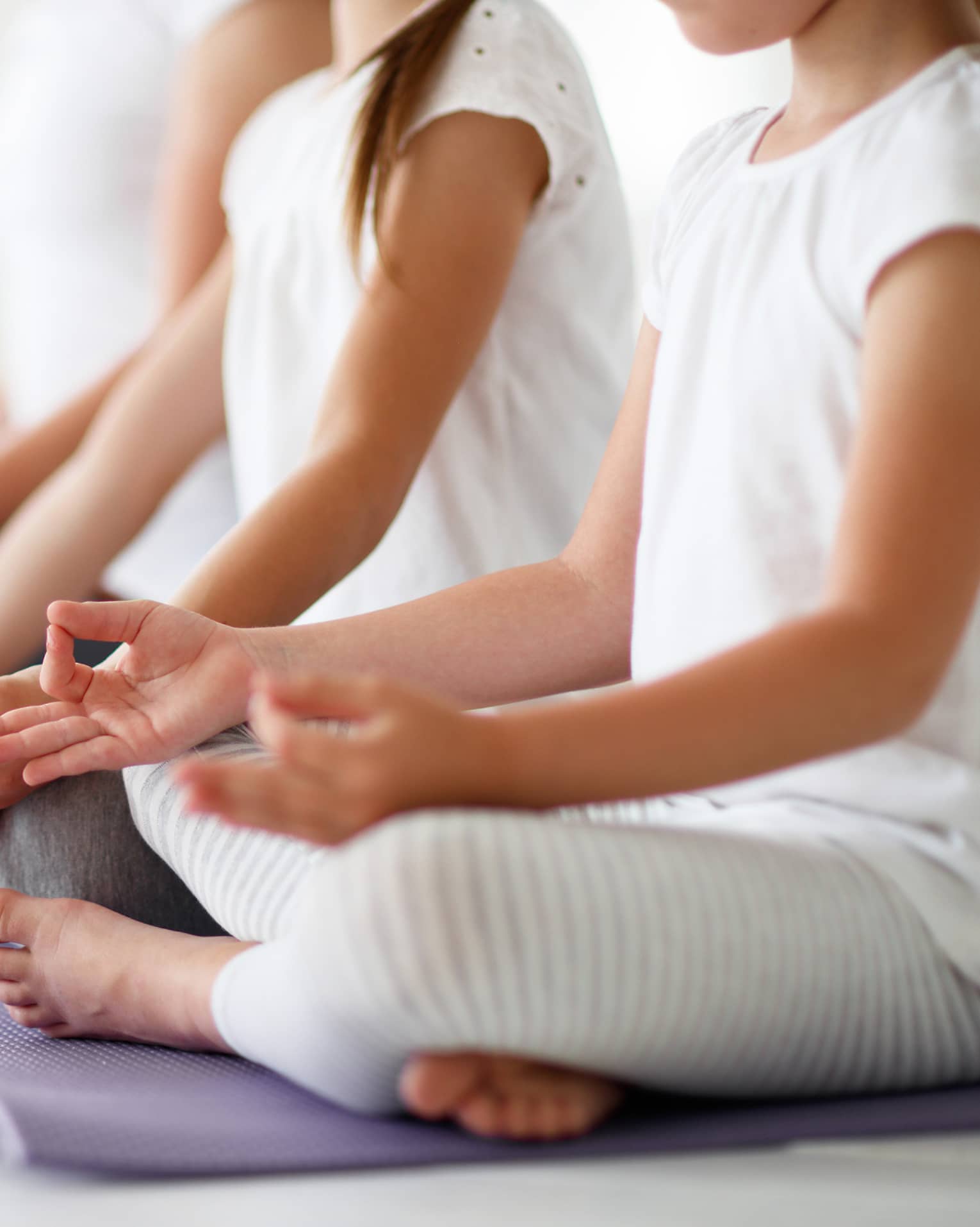 Young girls sit in cross-legged yoga pose