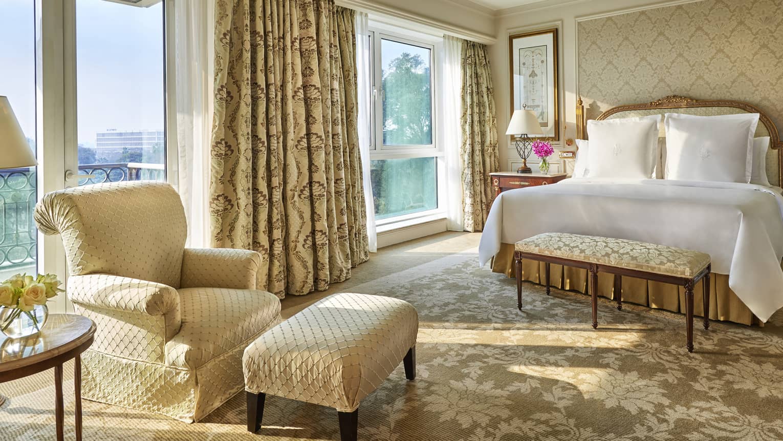Diplomatic Suite with soft beige and cream decor, bed and club chair with ottoman