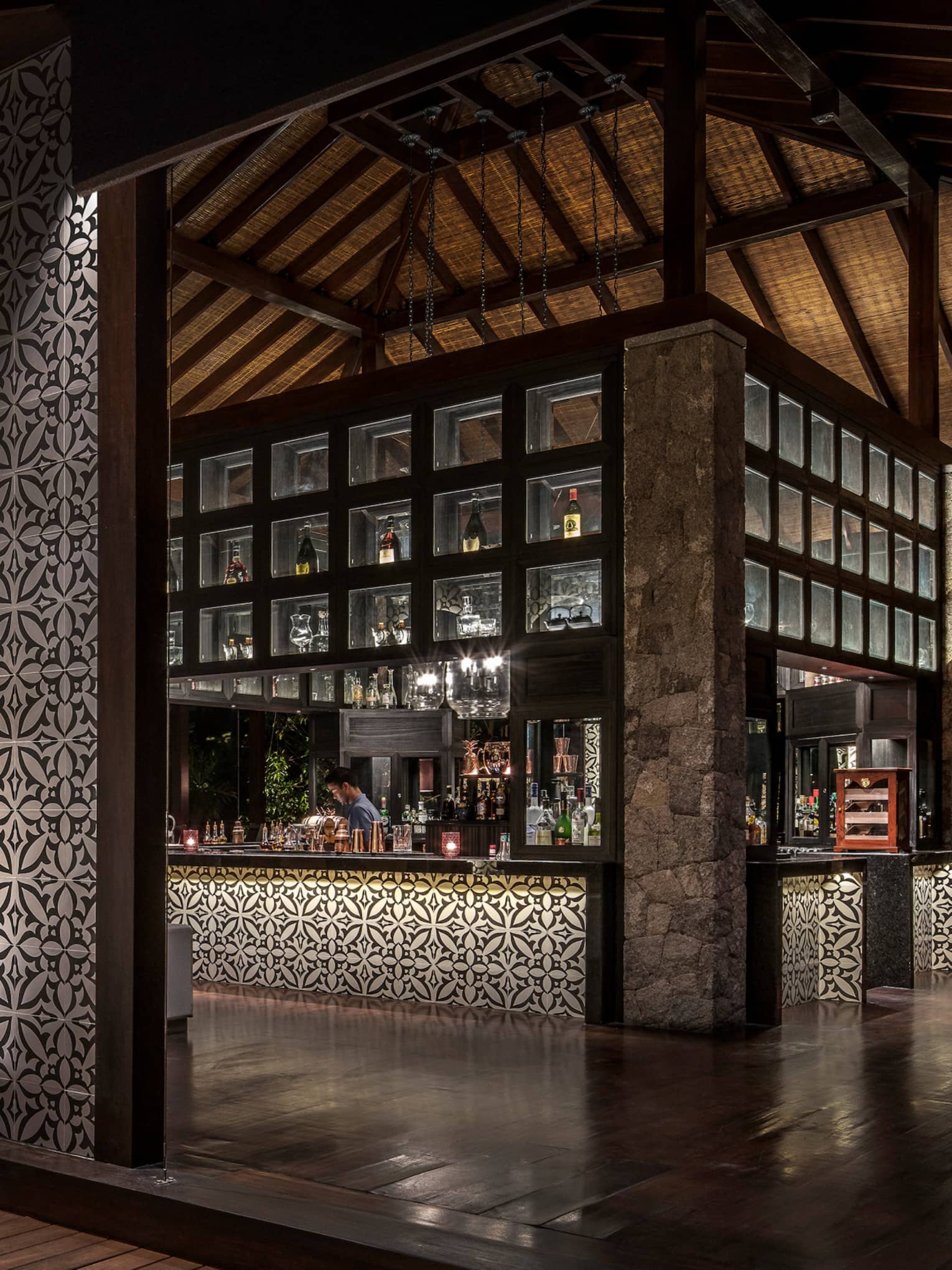 Bar interior, showing mosaic wall and mosaic lined bar with bartender and evening views out window