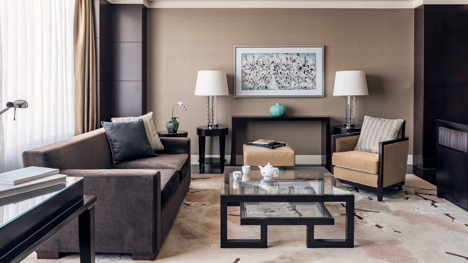 Brown coach, tan accent chair, glass nesting coffee table, brown and tan decor, floor-to-ceiling windows