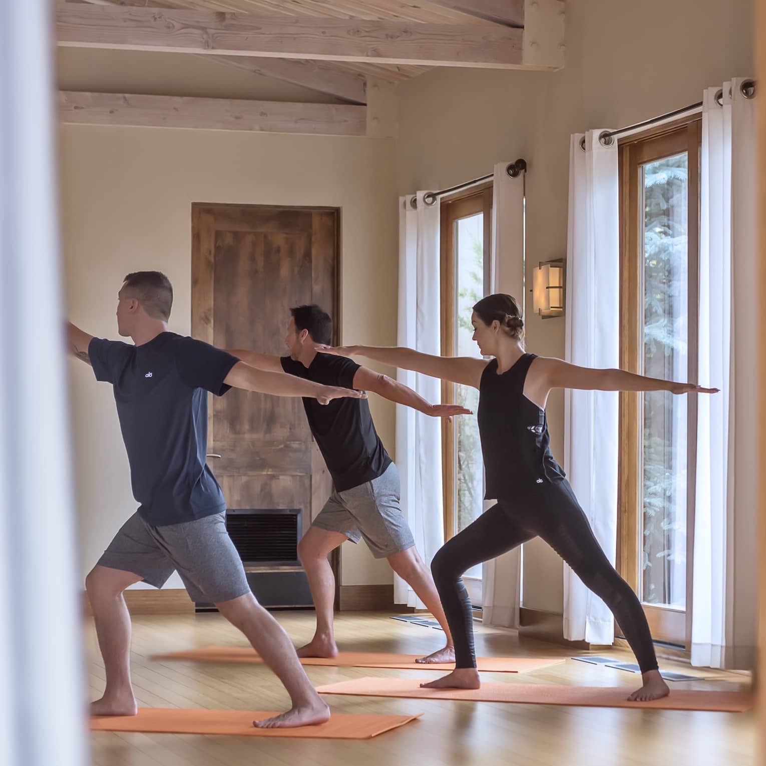 Three people perform yoga pose in Fitness Centre